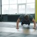 Young man is doing push-ups exercising in gym with female coach enjoying exercise indoors. Active millennials, sports and modern lifestyle concept.